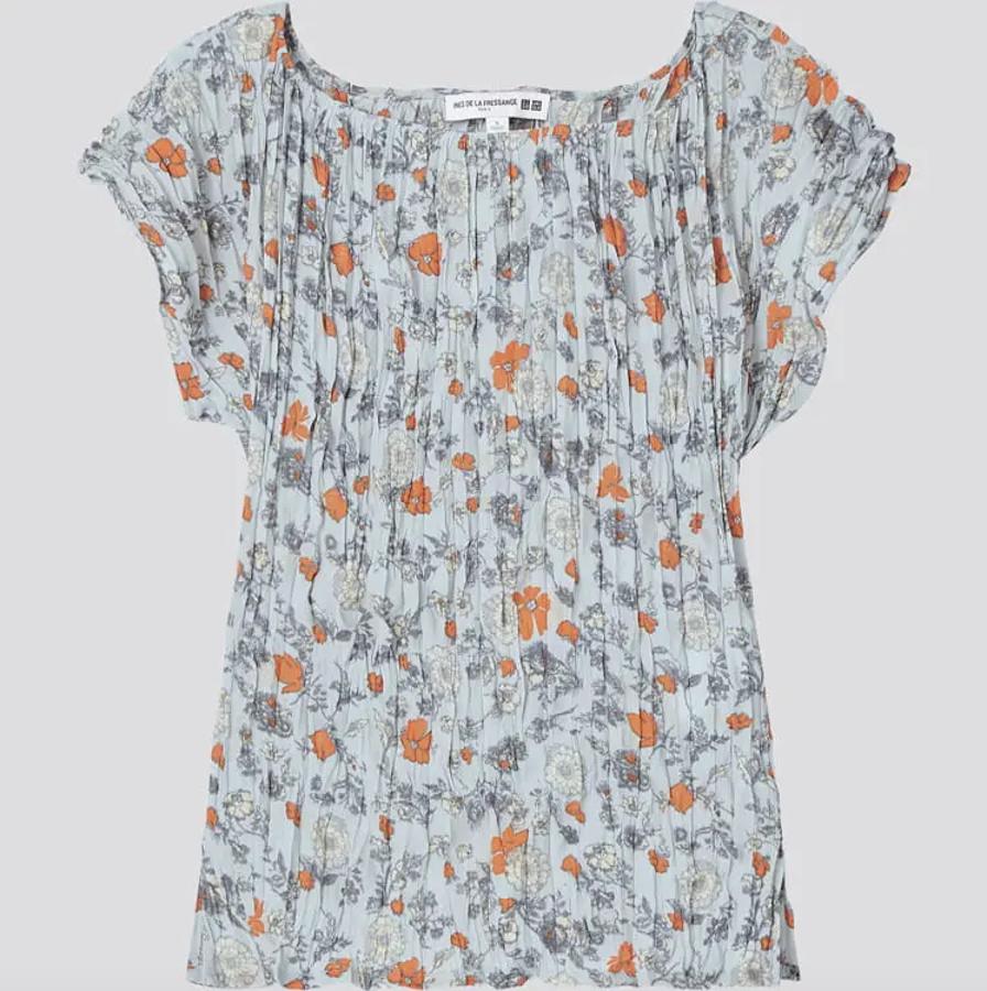 De fondo gris azulado con estampado de flores grises y naranjas, esta blusa plisada con cuello redondo y mangas cortas tiene un precio de 29,90 euros y estará disponible entre las tallas XXS y XXL.