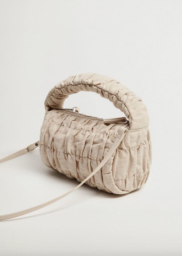 En algodón y lino con detalles fruncidos, este bolso en color crudo con asa corta y asa larga desmontable viene con cierre de cremallera metalizada y forro interior. Tiene un precio de 25,99 euros.