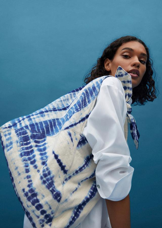 Diseño tie dye en tonos blancos y azules para este bolso saco confeccionado en algodón con detalle de nudo superior y cierre metálico de imán. Cuesta 29,99 euros.