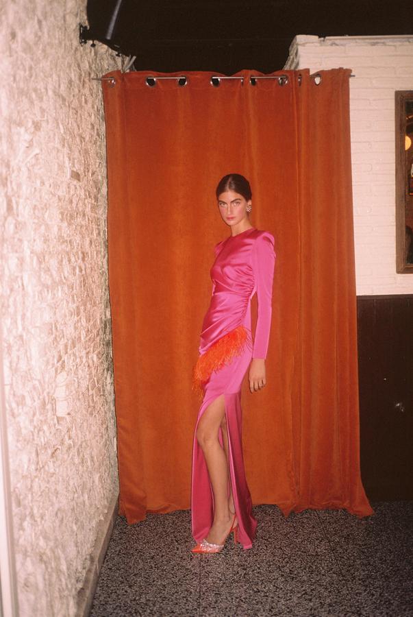 El vestido Carmen de Redondo Brand (239 euros) devuelve el block color a nuestra vida con esta sofisticada propuesta en fucsia y naranja en la que todos los detalles funcionan: el favorecedor drapeado del cuerpo, las hombreras con volumen, el detalle de las plumas de avestruz, la sensual abertura en la falda...