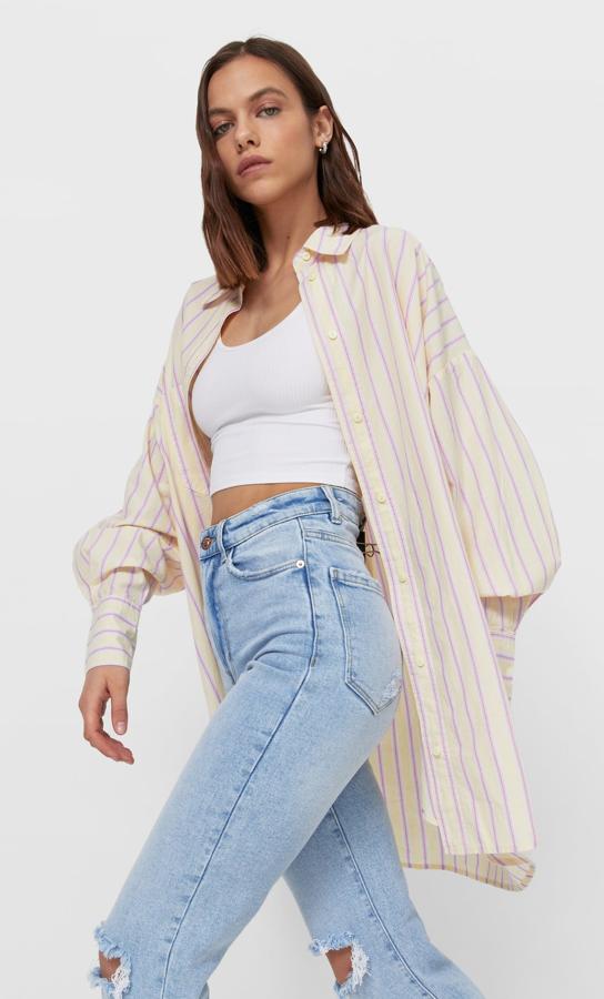 En popelín de color crudo con rayas en lila, esta camisa amplia con manga larga y cuello solapa tiene un precio de 19,99 euros.
