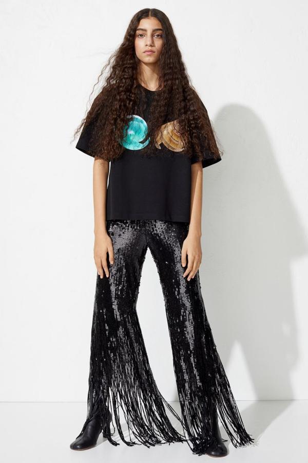Confeccionado en malla de lentejuelas de poliéster reciclado, este pantalón negro con cintura estándar y perneras rectas con bajos acampanados en malla holgada de lentejuelas tiene un precio de 129 euros y solo queda en las tallas 34 y 44.