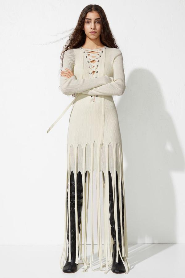 Este vestido de doble capa en color crema confeccionado en punto de canalé grueso de nailon y algodón orgánico viene con escote de pico pronunciado con lazada, mangas extralargas y falda multicapa con flecos largos en el bajo. Tiene un precio de 99 euros pero si nos gusta tendremos que encomendarnos a la bondad de la firma porque se ha agotado en todas las tallas.