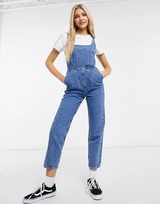 Escote cuadrado, tirantes, diseño ajustado, lavado medio, pantalón mom fit...Mono vaquero de Asos, ideal para estilismos casual super cómodos y estilizadores. (47,99 euros).