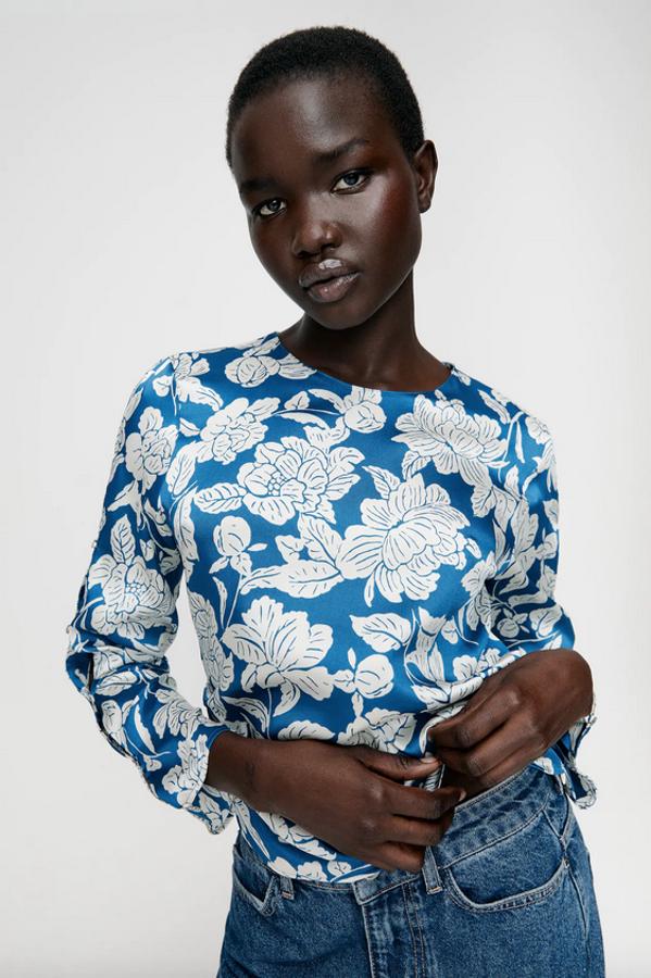 De cuello redondo y manga larga acabada en botones, esta camisa de Zara en azul con estampado de flores blancas viene con detalle de frunces en los costados y cierre posterior con botón y abertura y lateral con cremallera oculta. Podemos encontrarla entre las tallas XS y L por 25,95 euros.