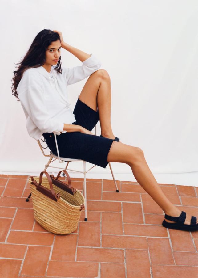 Look de la nueva colección de primavera de Mango con sudadera blanca y bermudas de color negro.