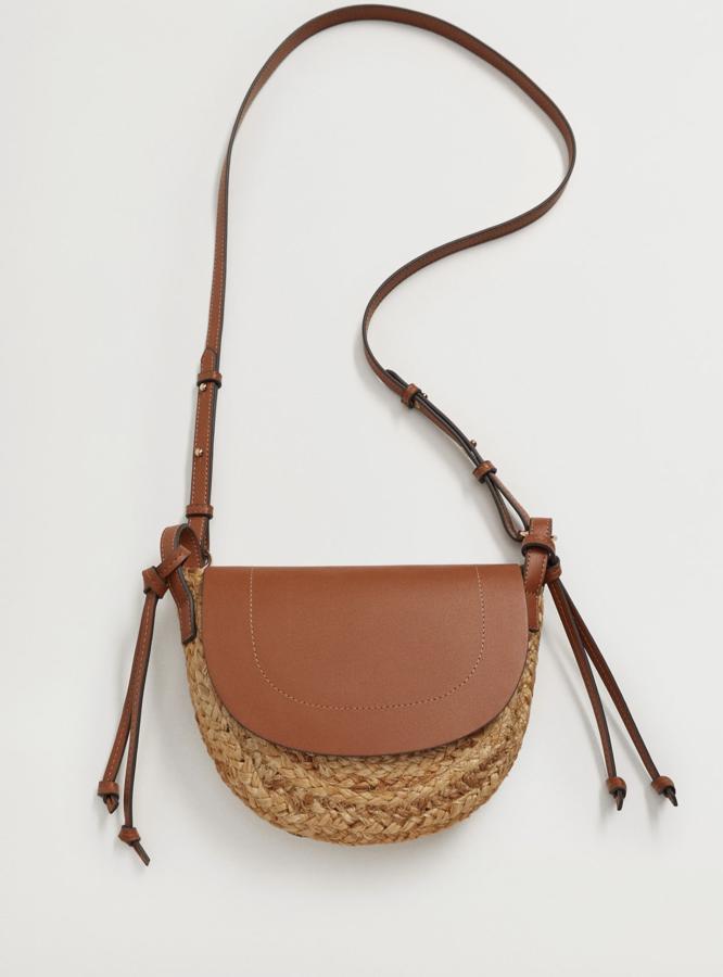 Este bolso de yute en color natural combinado con piel de color cuero cuenta con solapa frontal y nudos decorativos. Es de Mango y tiene un precio de 25,99 euros.