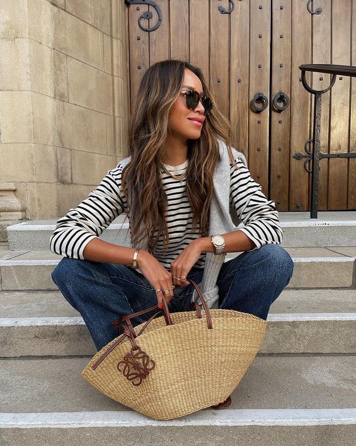 Camiseta de rayas, vaqueros rectos, capazo de rafia, jersey por los hombros y sandalias planas