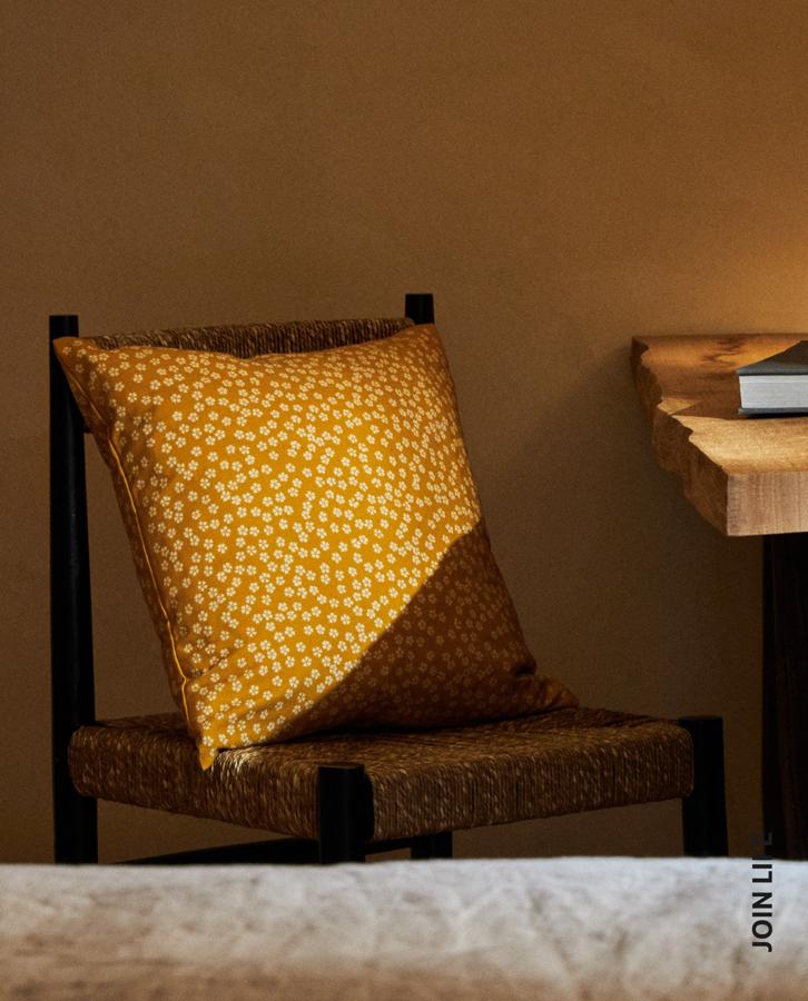 Este alegre cojín amarillo mostaza con estampado de flores japonesas cuesta 9.99 euros en Zara Home.