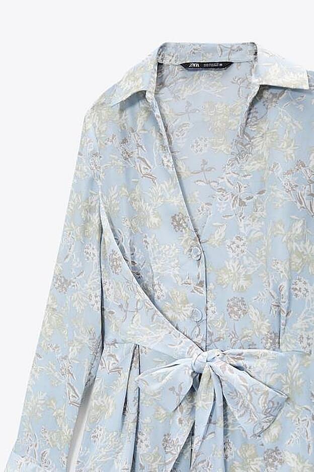 De corte midi y aberturas en los laterales, cuenta con un nudo en la parte delantera que ciñe la prenda a la cintura.