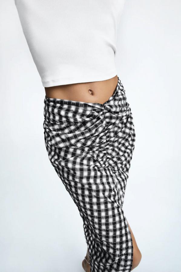 Con detalle de nudo en delantero, bajo con abertura frontal y cierre en la espalda con cremallera oculta en costura, esta falda midi de Zara con estampado de cuadros en blanco y negro está disponible entre las tallas XS y XL y tiene un precio de 22,95 euros.