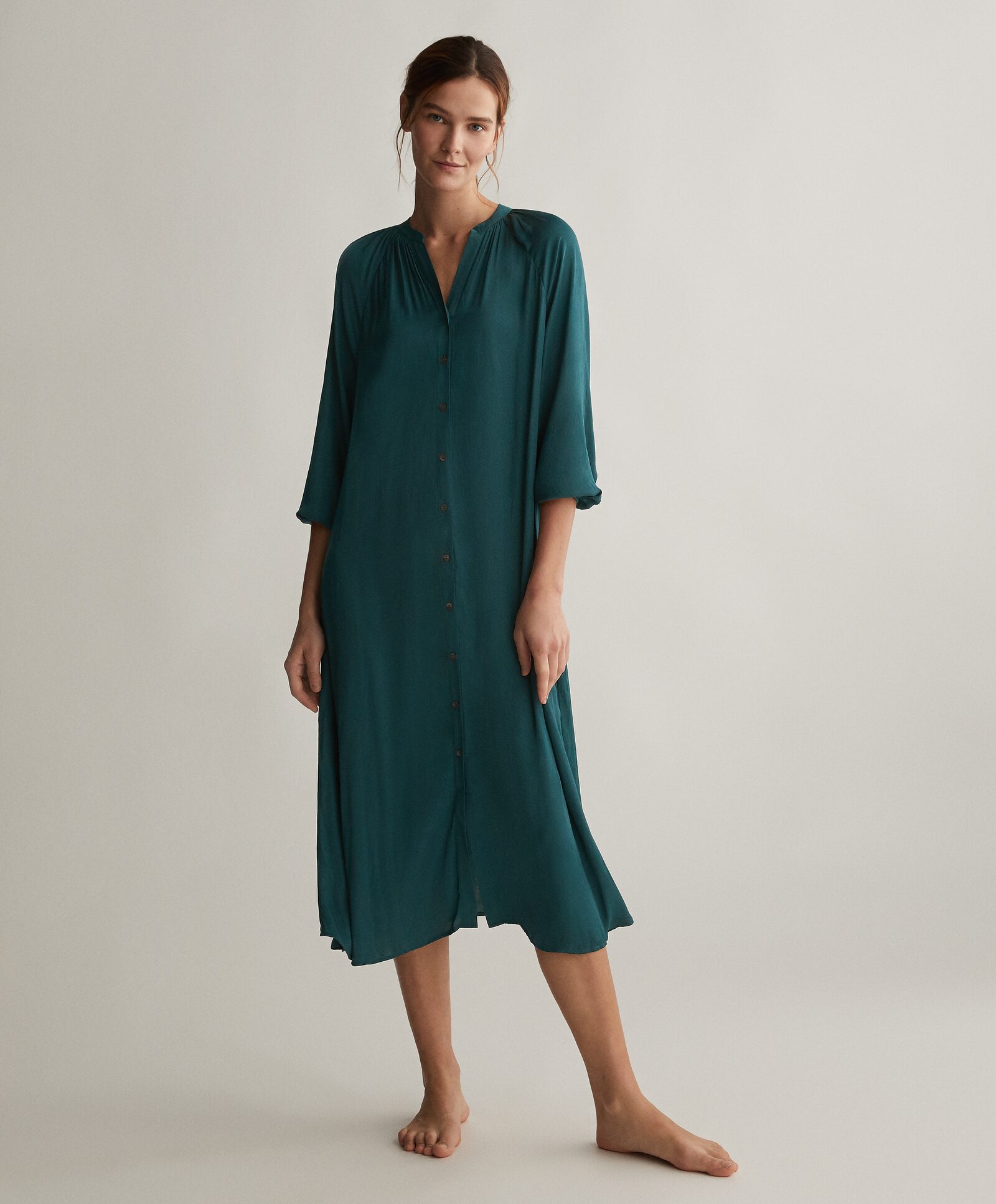 Satinado, suave, con cierre de botones de arriba a bajo, manga tres cuartos y cuello mao en el color más bonito y favorecedor: el verde que imita las plumas en el cuello de un pato. (35,99 euros).