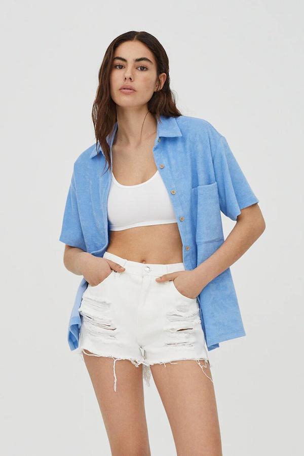 Este short vaquero mom fit en color blanco cuenta con detalle de rotos, bajo desflecado y cintura con trabilla. Es de Pull & Bear y tiene un precio de 19,99 euros.