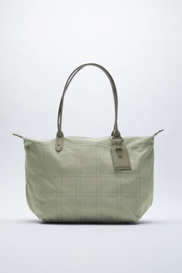 Disponible en varios colores, este bolso formato shopper con cuerpo de nylon cuenta con bolsillo delantero y asas de hombro. Su precio rebajado es de 15,99 euros (antes 22,95 euros).