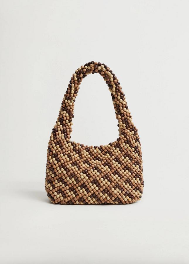 En color beige con cuentas en el cuerpo y las asas en marrón claro y oscuro y color natural, este bolso mini de Mango de asa corta y cierre de imán interior cuesta 3,99 euros.
