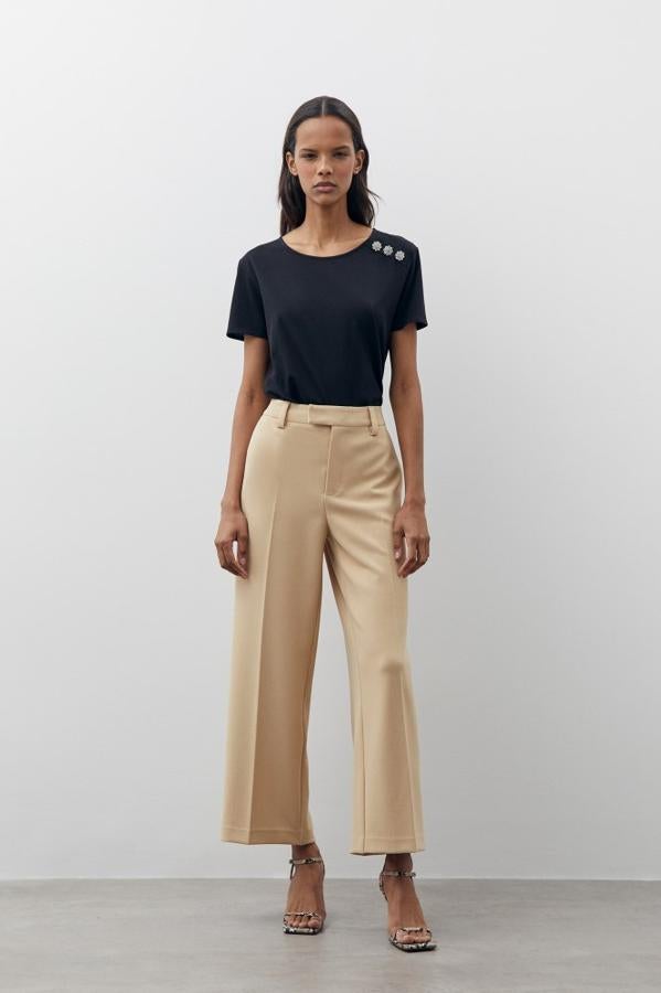 Una camiseta de manga corta con aplique de botones tipo joya disponible en negro, blanco y caqui. Junto a otras dos, tiene el precio más bajo de la lista: 7,99 €.