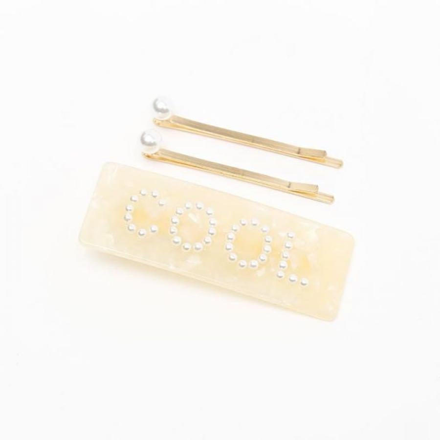 Moderno pasador en tonos beige con el texto 'COOL' con brillantes de imitación. Las horguillas son planas y doradas con una perla en uno de los extremos. Rebajado de 8,99 a 2,70 euros.