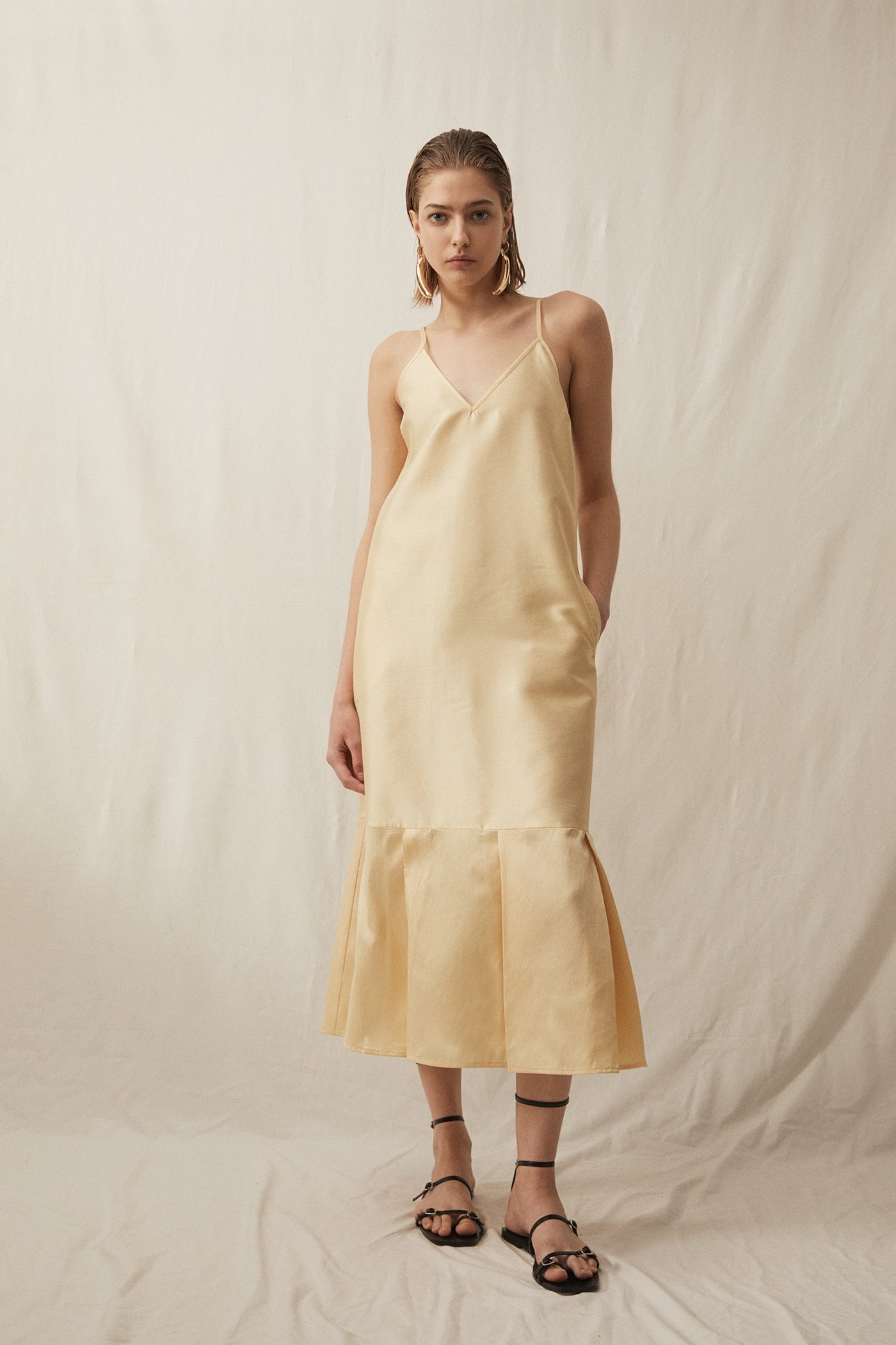 Otra idea sensacional para un look de invitada de primavera es este vestido midi con volante en el bajo en tafeta amarillo vainilla de Sfera (49.95 euros).