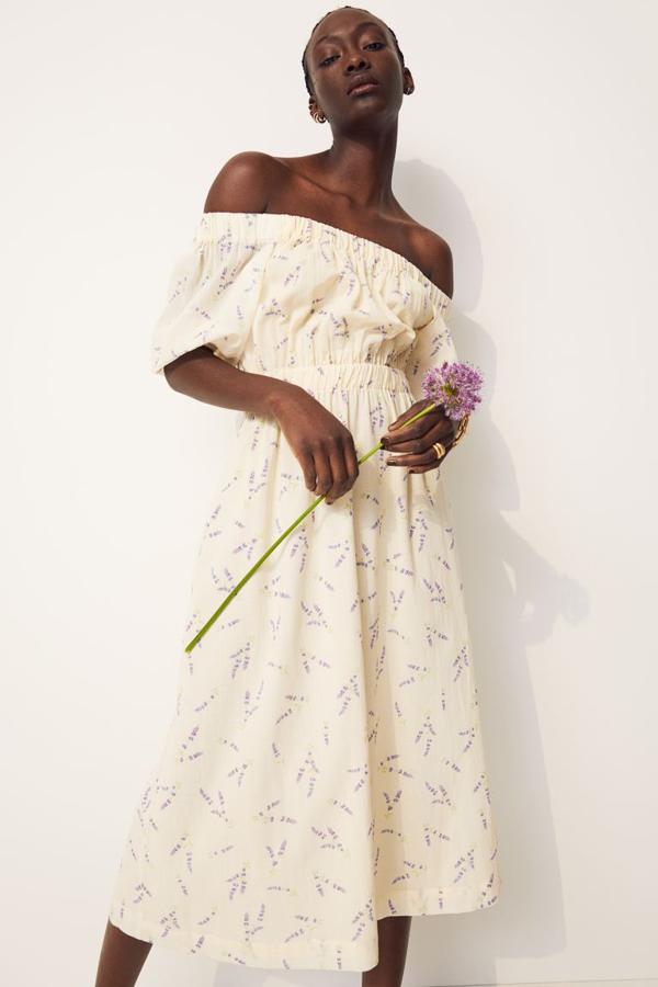 Diseño midi en tejido arrugado para este vestido en amarillo pastel con estampado lavanda, hombros al descubierto y sección cut-out en la espalda. Con corte elástico, mangas globo cortas con remate elástico y corte a la cintura con elástico revestido, está confeccionado en algodón orgánico, cuesta 29,99 euros y está disponible entre las XS y XXL.