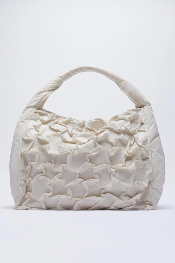 En formato maxi, este bolso tipo saca en color crudo cuenta con cuerpo con volantes y asa de hombros. Es de Zara y tiene un precio de 39,95 euros.