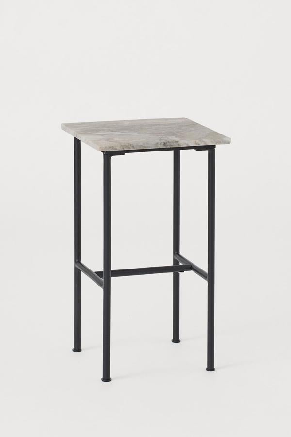 Con patas metálicas pintadas en metal pintado y tablero de mármol en color beige, esta mesa auxiliar tiene una altura de 53,5 centímetros, un largo de 30 y un ancho de 30. SU precio es de 99 euros.