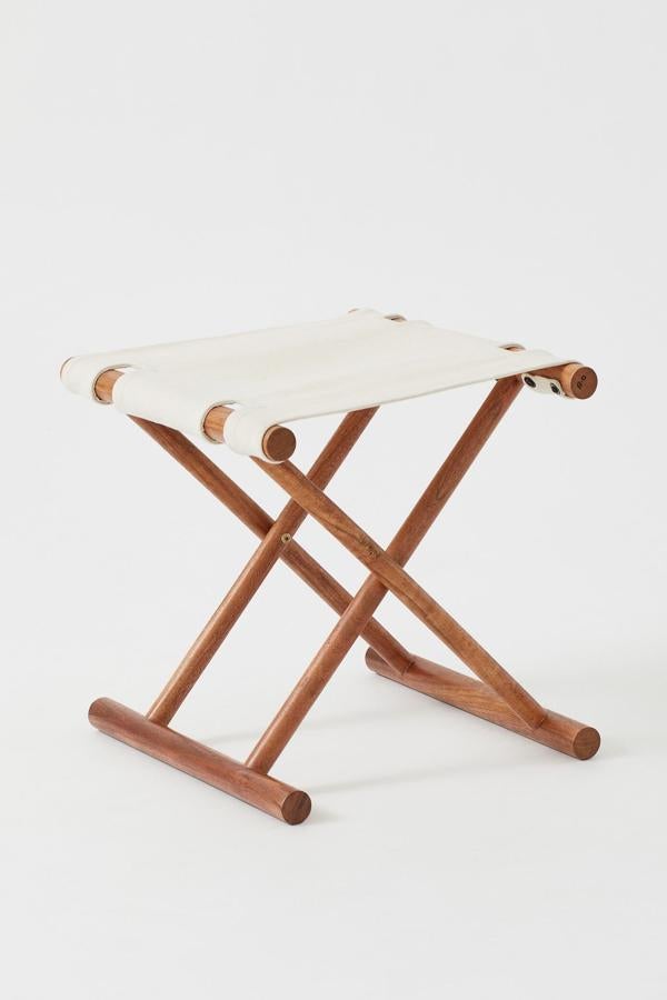 Este taburete plegable en madera de mango con asiento de lona gruesa en color crudo tiene unas medidas de 42x48, 5 centímetros y un precio de 49,99 euros.