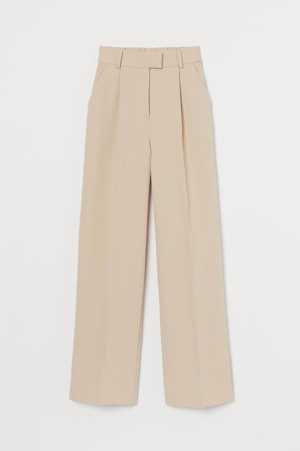 Confeccionado en sarga de mezcla de viscosa, este pantalón largo de talle alto con elástico revestido en la espalda viene con bolsillos laterales y perneras amplias rectas con raya. Es de H&M, cuesta 29,99 euros y está disponible entre las tallas 40 y 46.