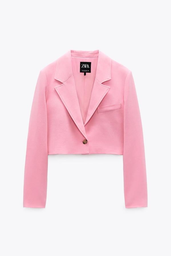 Esta blazer corta en color rosa chicle cuenta con hombreras y manga larga acabada en botones y cierre frontal cruzado con botón. Es de Zara y tiene un precio de 29,95 euros.