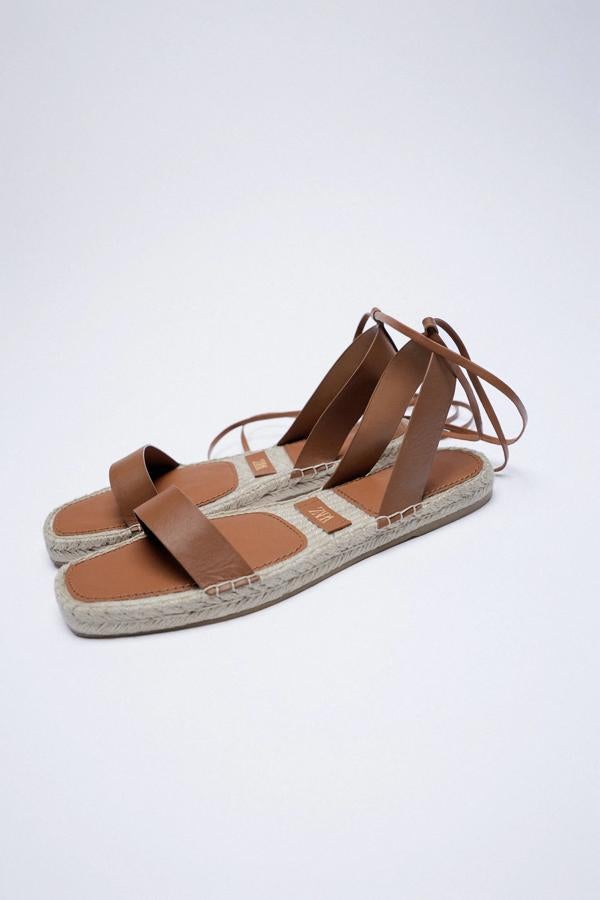Esta sandalia plana en piel de color marrón y suela forrada de yute tiene un cierre mediante atado de cintas y tiene un precio de 25,95 euros. Es de Zara.