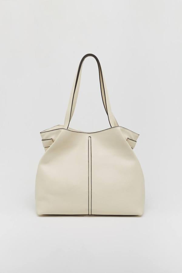 Las costuras crean un bonito contraste en este bolso color crudo con doble asa interior. No es el único que entra en la lista por muy poco (cuesta 19,99 €), pero es tan elegante que nos alegra especialmente no tener que dejarlo fuera.