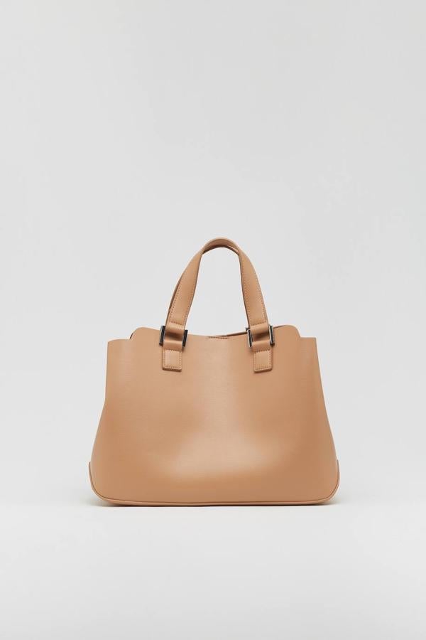 Si quieres apostar por la sencillez, este bolso rígido es para ti. Además de las asas cortas, tiene una tercera larga extraíble, por lo que puedes adaptarlo según cuáles sean tus necesidades. Está disponible en crudo y en beige por 19,99 €.