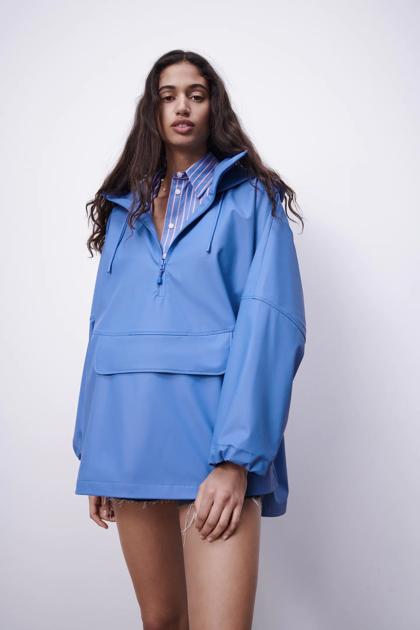 Nuestra primera apuesta va para un chubasquero de Zara resistente al agua en un color azul eléctrico precioso y un diseño con bolsillo de canguro, capucha ajustable y bajo asimétrico muy favorecedor. Nos encanta la idea de combinarlo con una camisa de rayas en azul bebé como propone la firma de Inditex. (39,95 euros).