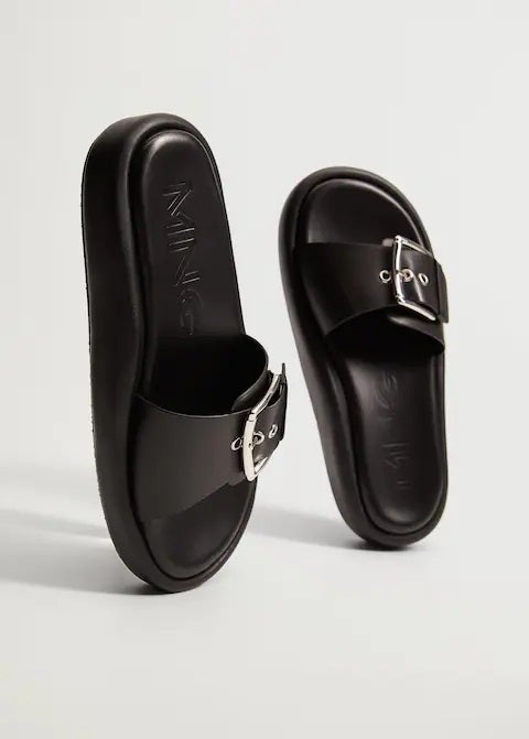 Y hablando de negro, estas sandalias planas con hebilla de Mango van a combinar con todo tu armario. (39,99 euros).