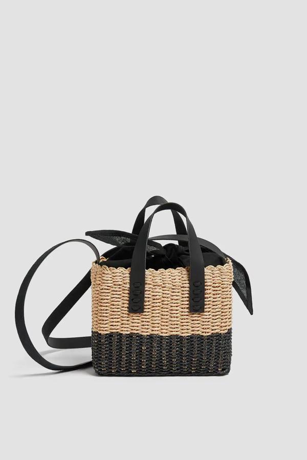 En beige y negro, este bolso bandolera de papel trenzado cuenta con asas de mano y de hombro y detalle de cierre mediante lazada. Tiene un precio de 17,99 euros.