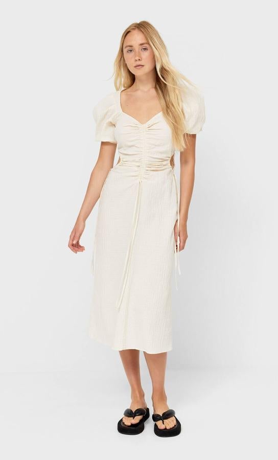 En color blanco piedra, este vestido midi con escote de pico y manga corta abullonada cuenta con aberturas laterales y tiene un precio de 29,99 euros.