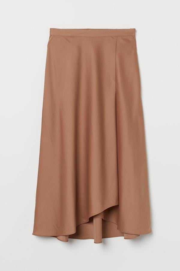 De satén en color beige oscuro, esta falda midi tipo pareo con bajo asimétrico y tiene un precio de 29,99 euros.