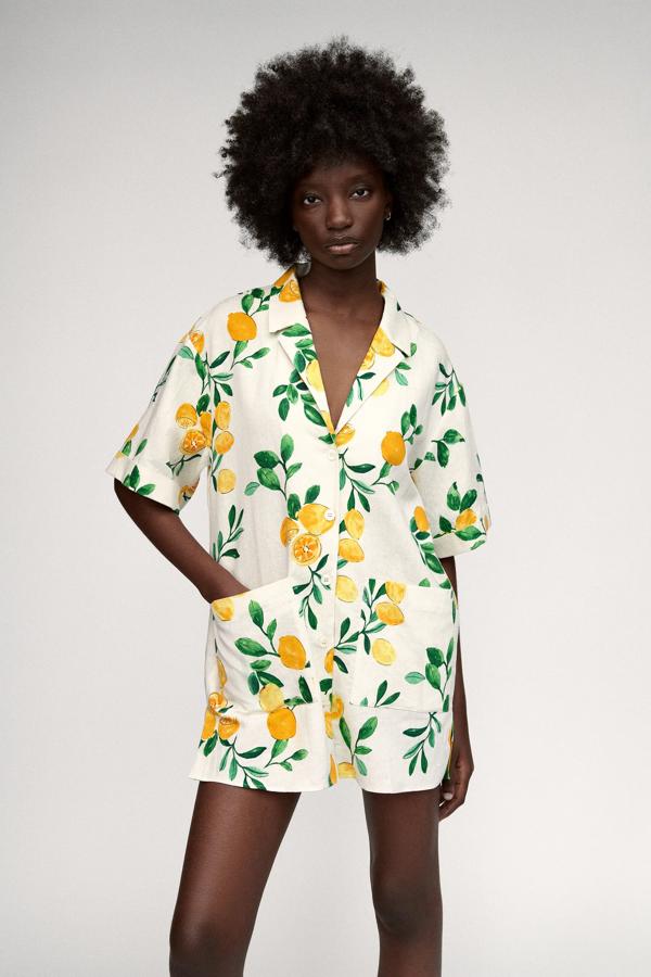 En color blanco roto con estampado de limones, este vestido corto con cuello y solapa cuenta con aberturas en los laterales y cierre frontal mediante botones. Tiene un precio de 29,95 euros.