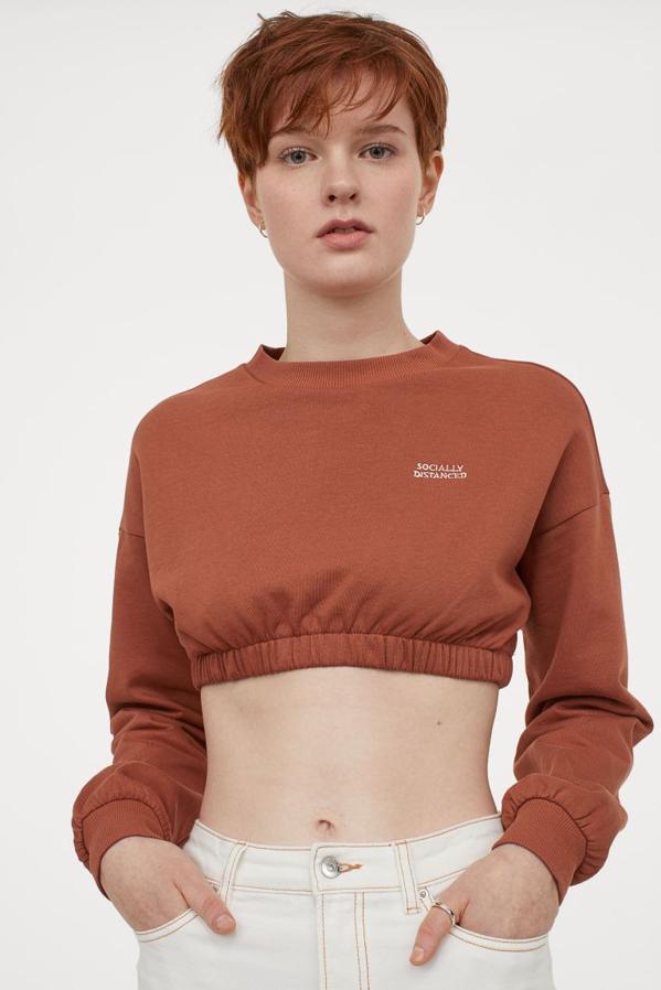 En marrón chocolate, con diseño de hombros caídos, cuello y puños en elástico de canalé y elástico revestido en el bajo, esta sudadera de H&M tiene un precio de 14,99 euros y está disponible entre las tallas XXS y XL.