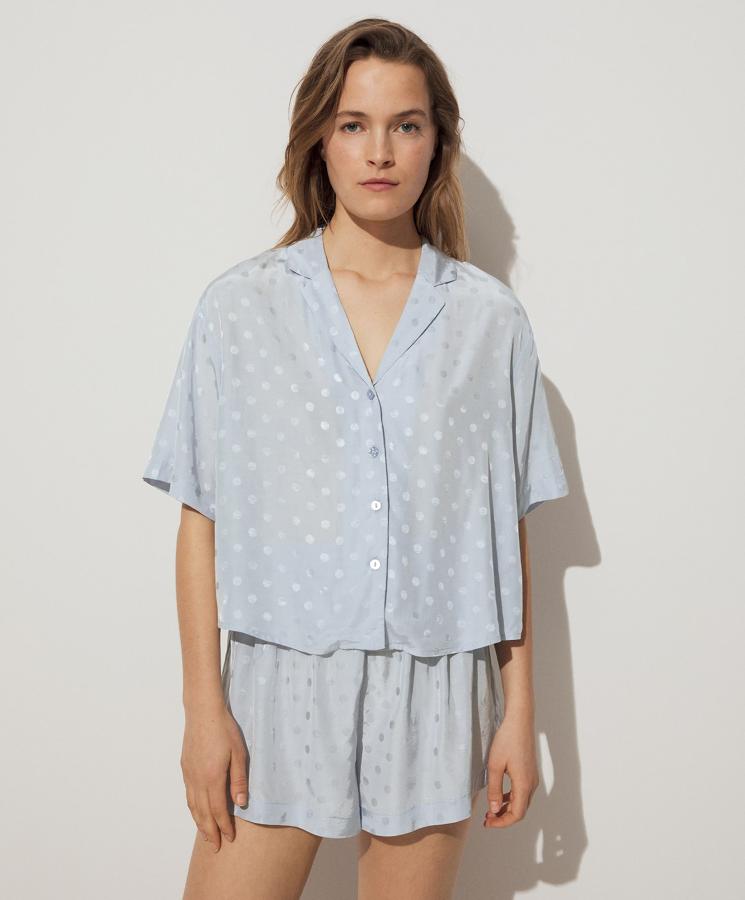 En tejido jacquard con estampado de topos en color azul, este pijama cuenta con short corto (15,99 euros) y camisa (22,99 euros) de manga corta con cierre mediante botones.