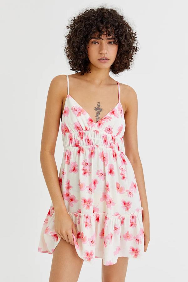 En color blanco con flores en fucsia, este vestido corto con tirantes finos, escote de pico y volantes y tiene un precio de 22,99 euros.