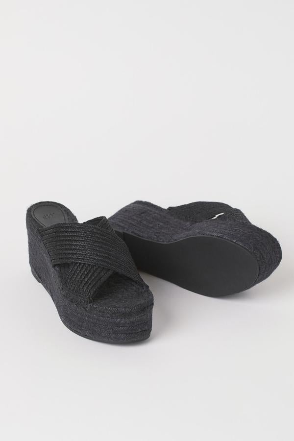 Disponibles en negro o en beige, estos mules en mezcla de yute con turas anchas cruzadas y cuña tienen un precio de 49,99 euros.