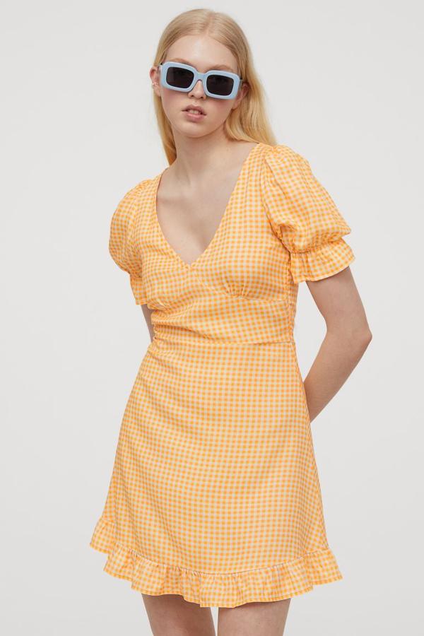 Con diseño de cuadro vichy en color yema y blanco, este vestido corto de H&M con escote de pico y costura bajo el pecho viene con mangas cortas abullonadas con elástico y ribete de volante, tiras cosidas en la parte posterior de la cintura y cremallera oculta en un lateral. Cuesta 14,99 euros y está disponible entre las tallas 32 y 50, y en negro con diseño de puntos y en rojo con flores blancas.