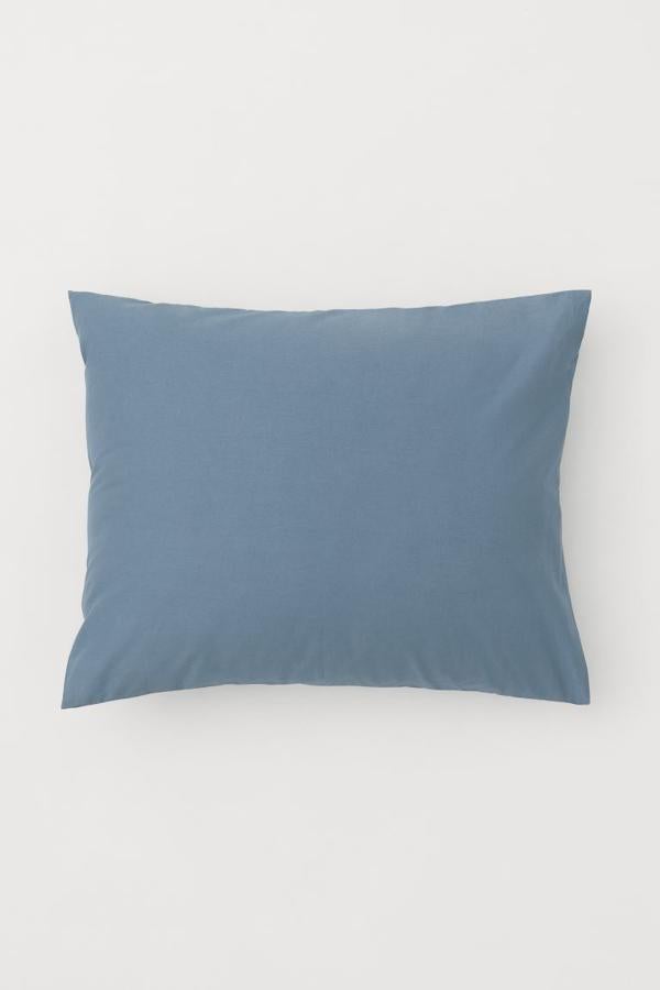 Para darle un toque mediterráneo al dormitorio, la clave es añadir textiles en tonos azules. Si tienes una funda nórdica en blanco, cambia las fundas de cojín. Esta funda es de H&M Home y cuesta 4,99 euros.