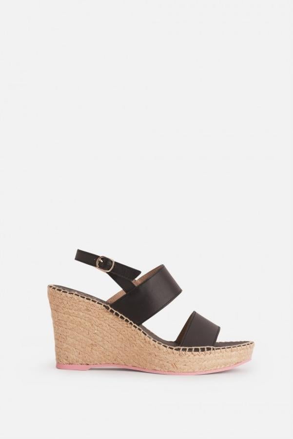 Cuña con abertura en la parte delantera, cierre en el tobillo. Doble tira de piel y esparto en tono natural. Lleva la suela en color rosa (99 euros).
