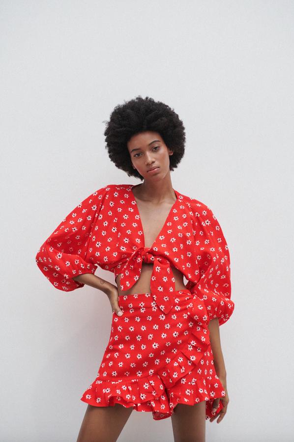 Confeccionada con al menos un 50% de lino sostenible, esta falda pantalón de Zara en color rojo con estampado de flores blancas viene con delantero cruzado con lazo tipo pareo y acabado en volantes. Podemos encontrarla entre las tallas XS y XL por 22,95 euros.