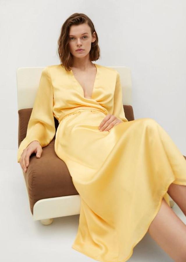 En Mango encontramos este elegantísimo vestido midi de satén amarillo suave, muy favorecedor con su escote cruzado. Cuesta 59.99 euros.