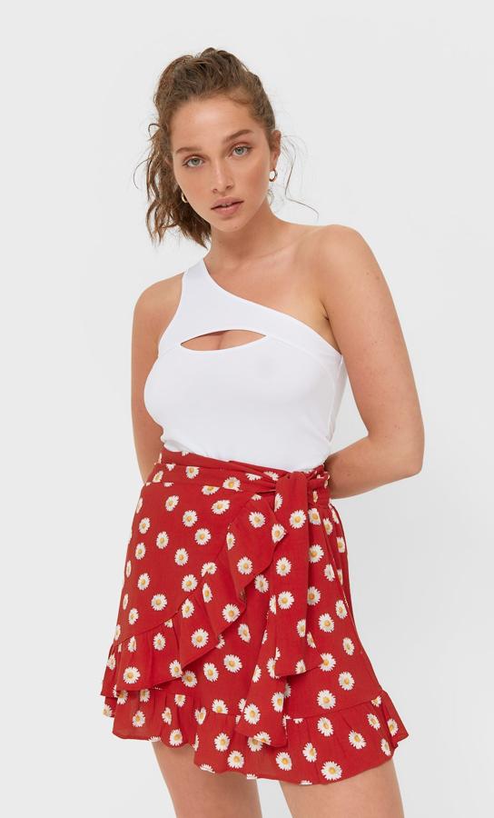 En color rojo con estampado de margaritas, esta falda pareo de tiro alto y con lazada tiene bajo acabado en volantes y un precio de 15,99 euros. Es de Stradivarius.