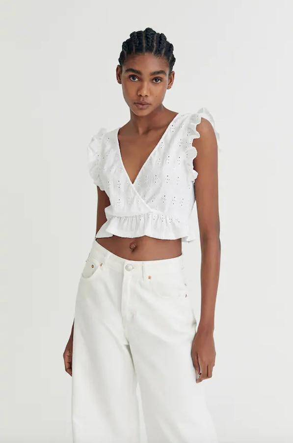 Con bordado suizo en toda la prenda, este top blanco de manga sisa de Pull&Bear viene con escote de pico cruzado u detalles de volantes en las mangas y el bajo. Podemos encontrarlo entre las tallas XS y XL por 12,99 euros.