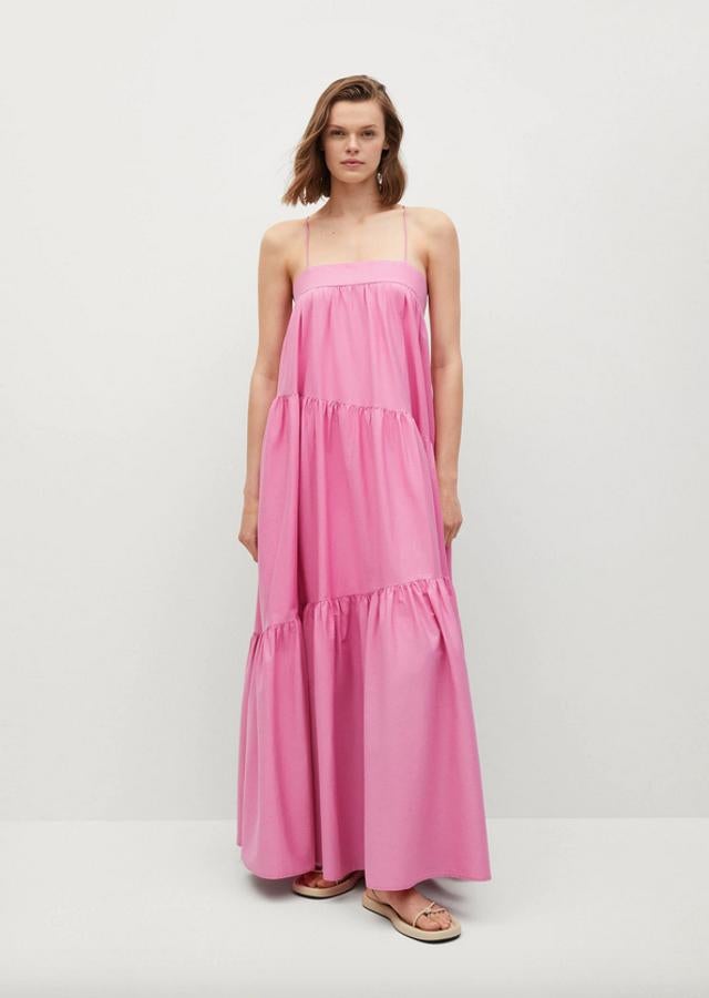 En rosa chicle, confeccionado en tejido fluido y diseño maxi, este vestido largo de Mango de diseño acampanado viene con escote recto, tirantes finos cruzados en la espalda y detalles plisados. Cuesta 5995 euros y está disponible entre las tallas XS y XL.