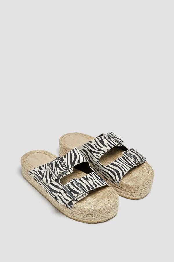 Con estampado de cebra, esta sandalia con dos tiras en la parte delantera y cierre mediante hebilla cuenta con cuña de yute y tiene un precio de 29,99 euros.